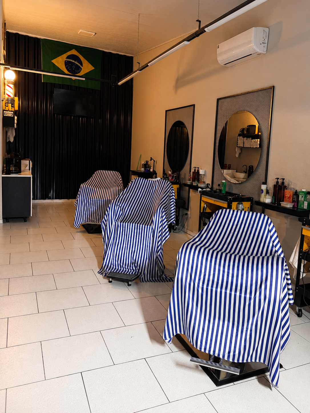 Interior da BA Barbershop com cadeiras, espelhos e poste de barbeiro, em Piraquara/PR